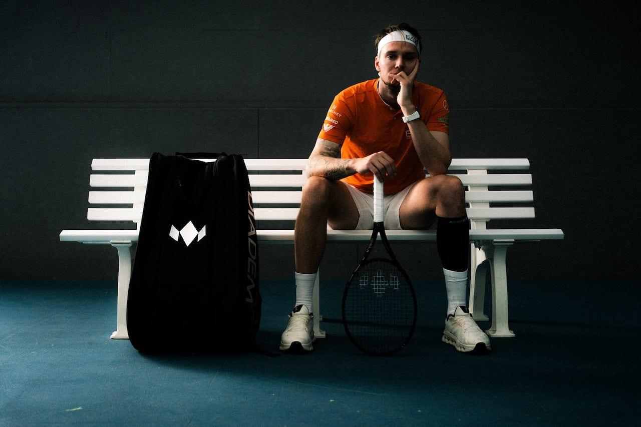 Alexander Bublik sitting courtside with a Diadem bag and racket